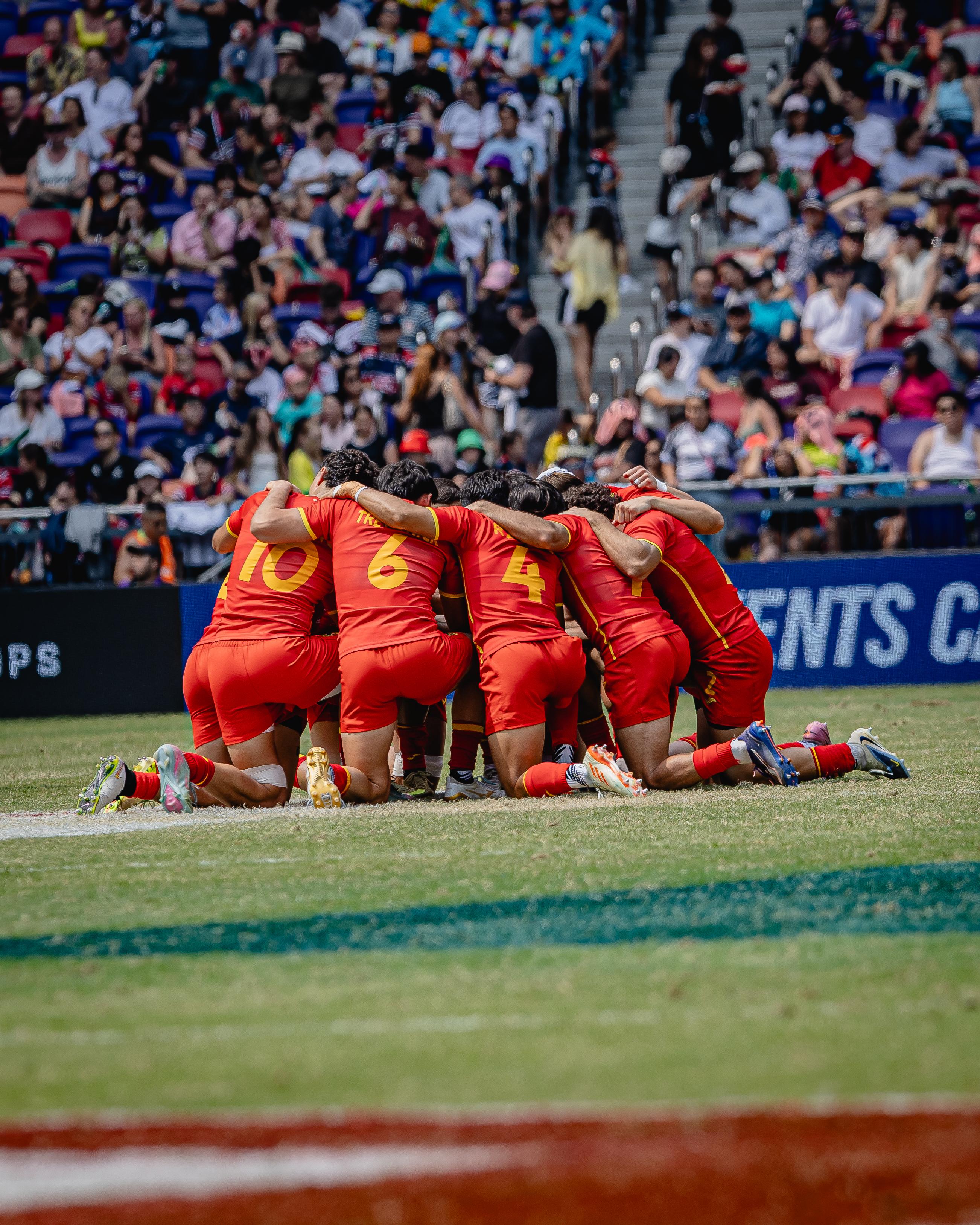 Un equipo de rugby reunido en círculo sobre el césped antes de jugar